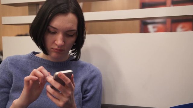 Young attractive woman using smartphone sitting in cafe.
