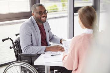 Portrait of male invalid who can`t go, sits in wheelchair, being paralysed, still work in his own...