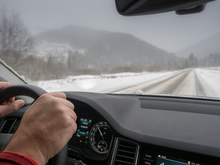 Driving in snowy weather. View from the driver angle while hands on wheel.