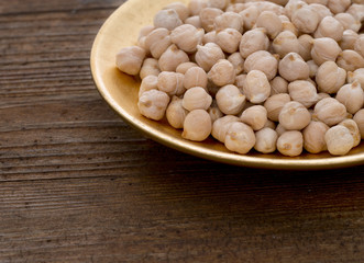 Chickpeas on gold colour plate, closeup.