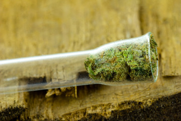  Medical Cannabis - small glass pipe with medical marijuana flowers inside on the natural oak wood background.