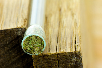  Medical Cannabis - small glass pipe with medical marijuana flowers inside on the natural oak wood background.