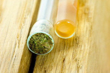Medical Use of Cannabis - small glass pipe with medical marijuana ready for use on the oak natural wood.
