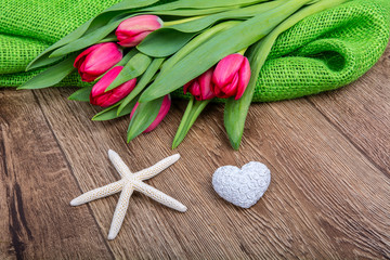 Starfish, heart and tulips on a wooden table