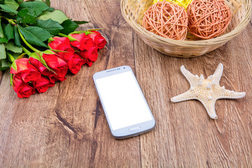 Mobile phone, starfish and roses on a wooden table