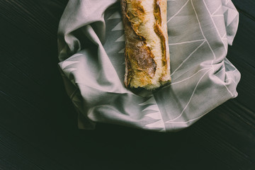 Fresh bread french baguette on a cloth and black wood, moody dark food photography