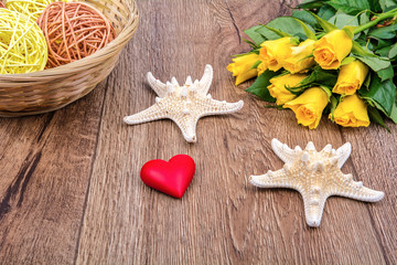 Starfishes, heart and roses on a wooden table