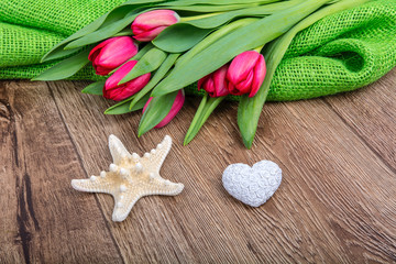 Starfish, heart and tulips on a wooden table