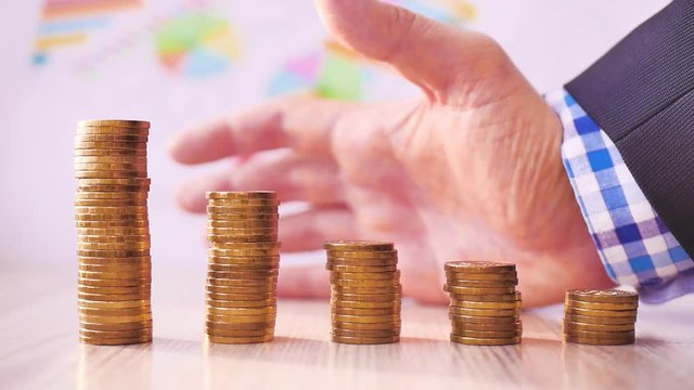 Man hand holding coin dollar on money coin stack arranged as a graph on wooden table. Hand of male or female finger step coins stack growing growth saving money. Business idea.