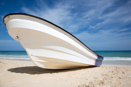 Motorboot fuer Taucher oder Anglerboot? Heroshot eines kleinen Motorbootes am strand liegend. Dahinter Das Meer mit Wellen und leicht bedekter Himmel.