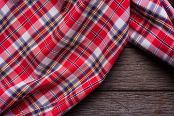 Flat lay view of tartan textured scarf on wooden background.