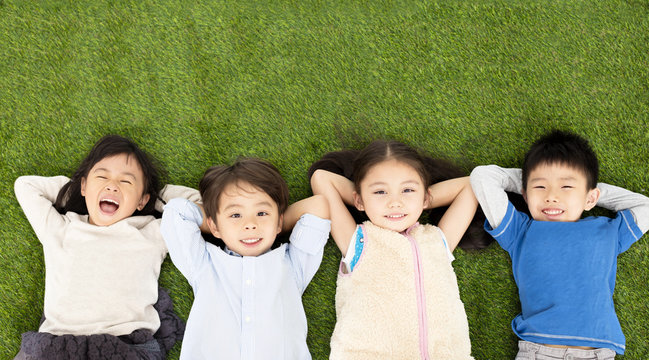happy boys and girls lying on green grass.