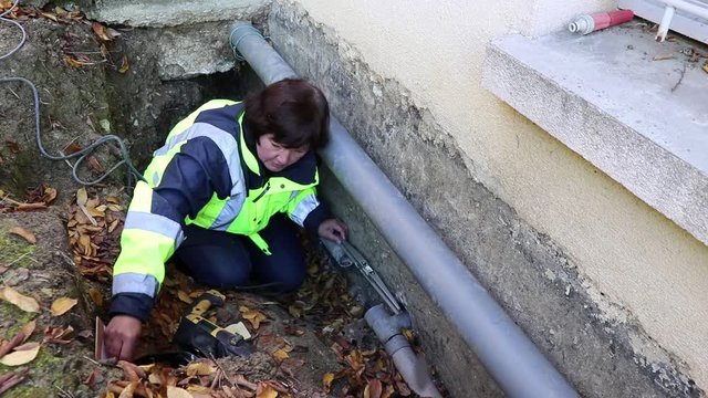 A woman plumber checks the horizontal position of the water pipes for fixing.