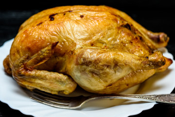 roast chicken on a white plate, on a black wooden background
