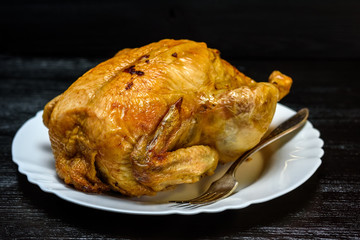 roast chicken on a white plate, on a black wooden background