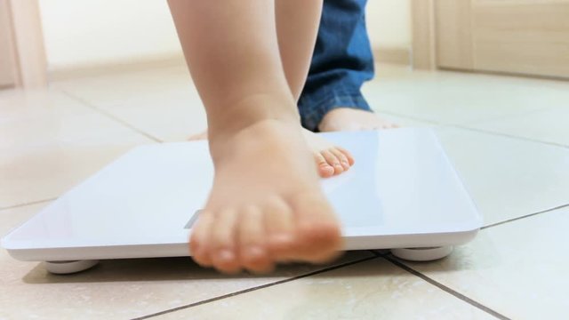 4k closeup video of baby and mothers feet standing on weight scales