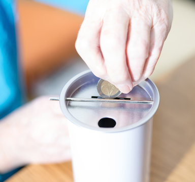 M&uuml;nzgeld wird eine Spendendose gesteckt