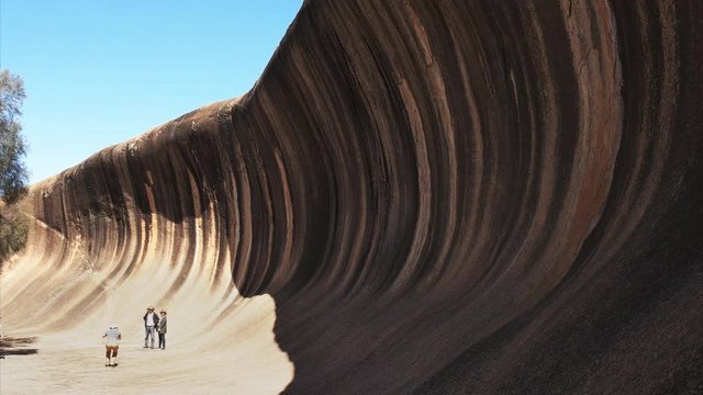 tourists pose for a photograph at the unusual rock formation in western australia known as wave rock