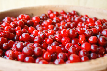 Red berries in a wooden bowl. Ripe berries close-up