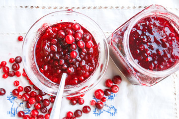 Jam in a bowl, berries and a jar of jam on a white tablecloth