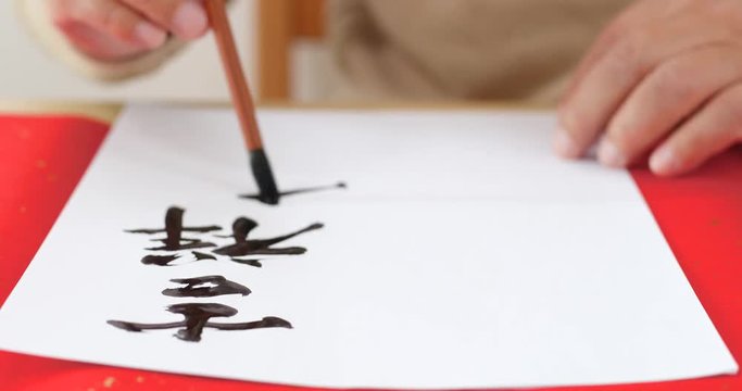 Writing Chinese calligraphy with phrase meaning wish you good fortune and may all your wishes come true