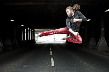 a young man makes a karate jump on the street