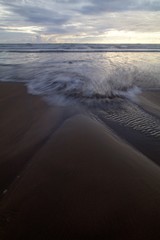 The incoming tide on a beach in Cornwall , England.