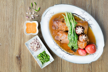 Stewed pork leg in white dish on wooden background with dim light. Asia food and still Life and selective focus.