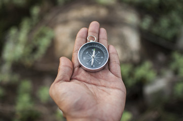 Compass in the hand against mountain. Adventure end travel background.