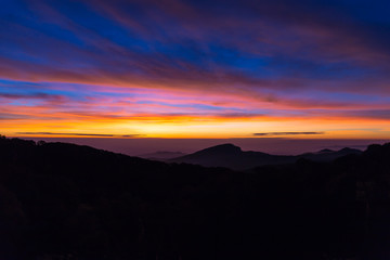 Morning mist in the mountains, bright blue sky, clouds in the foreground.
