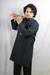 young indian male model in black kurta playing flute © pathakdesigner