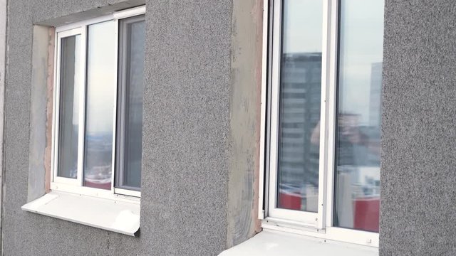 Young man smoking cigarette through the window of house. Man smoking by the window