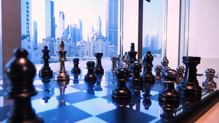 Checkerboard near the window. Figurines of the award in the form of a gold chess queen stand in front of the window. chess board game concept of business ideas and competition and strategy ideas