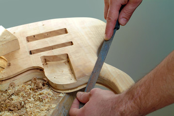 lutist working on electric guitar filing the wood of the instrument
