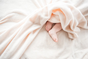 Close up of plump child legs relaxing on daybed under mild plaid. Copy space in left side