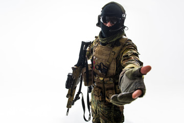 Portrait of serene soldier wearing balaclava offering arm. He keeping assault rifle. Army and protection concept. Isolated and copy space