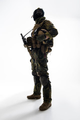 Full length side view grave defender telling by gadget while holding assault rifle in hands. Military concept