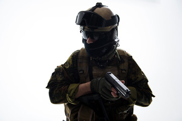 Portrait of stern soldier wearing uniform while holding modern pistol in hands. Military concept. Isolated