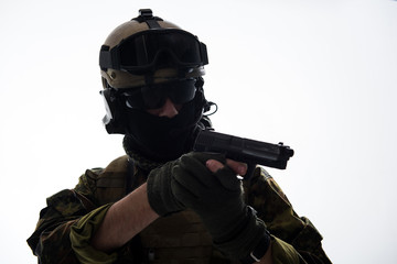 Portrait of serious defender in helmet and balaclava shooting with gun. Army concept. Isolated