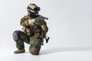 Portrait of serious defender kneeling while shooting with gun. Protection and attack concept. Copy...
