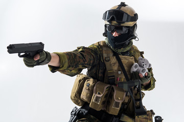 Portrait of stern warrior shooting with gun while holding fluffy toy in hands. Protection concept