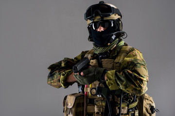 Obraz premium Portrait of orderly man in modern helmet and balaclava firing weapon. Army concept. Isolated and copy space