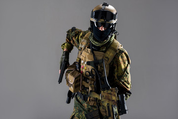 Portrait of grave soldier holding gun in arms. He wearing special ammunition. Uniform and military...