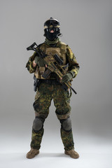 Full length portrait of stern soldier keeping assault rifle in hand. Army concept