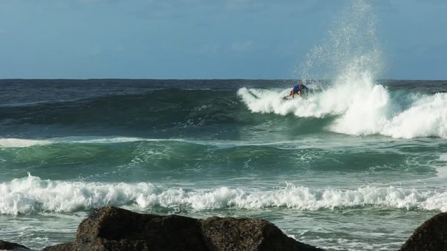 spectators watch a surfer riding a wave at snapper rocks on the gold coast of australia