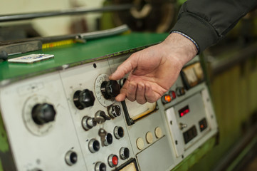 Factory worker adjusts the control panel of industry machine