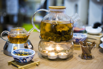 Fototapeta na wymiar Blooming Flower Tea in Glass Tea Pot with traditional chinese accessories stay on the table in teashop