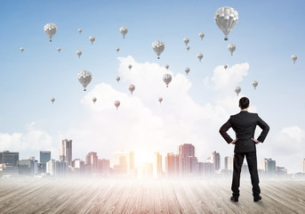 Motivation and inspiration concept with modern cityscape and businessman observing it