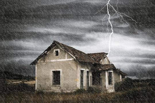 a storm with rain and a thunderbolt over a scary old abandoned house in the countryside