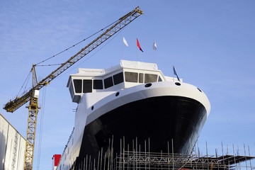 Shipbuilding construction in progress with tower crane blue sky port harbor harbour greenock glasgow Scotland uk